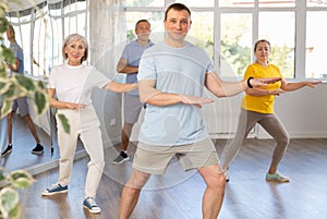 Positive instructor leading zumba class for seniors in fitness studio