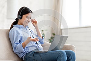 positive korean lady using headset and laptop at home