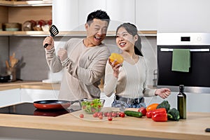 Positive korean man and woman cooking together at home