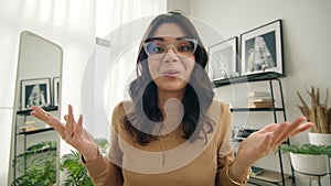 Positive Latin American businesswoman in eye glasses talking to camera at work