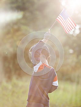 Positive little boy with american flag and celebrating 4th of july, independence day, or memorial day.