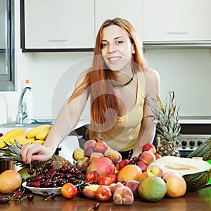 Positive long-haired woman with heap of ripe fruits
