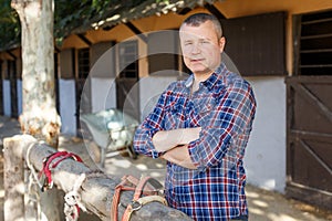Positive male farmer with belly-band standing at stable outdoor