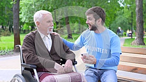 Positive male volunteer entertaining disabled patient, listening music together