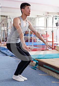 Positive man acrobat exercising gymnastic action at sport gym
