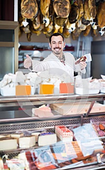 Positive man butcher showing sorts of meat