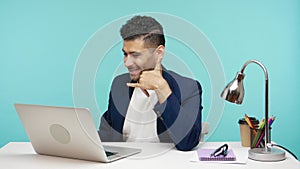 Positive man chatting via web camera on his laptop asking to call him showing phone gesture, flirting, online date