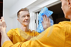 Positive man cleaning mirror with cleaning cloth at home