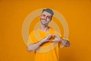 Positive man doing heart gesture and looking at camera while standing isolated