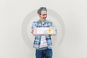 Positive man with festive mood giving present box, celebrating friend's birthday, congratulating