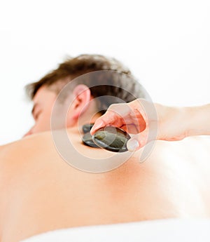 Positive man having a back massage with hot stones