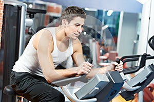 Positive man at legs bicycle exercises machine