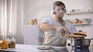 Positive man listening music and cooking vegetables, healthy low-calorie eating
