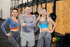Positive man and young women in activewear posing during CrossFit workout in gym fitness center