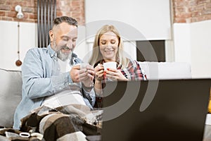 Positive mature couple using laptop during free time at home