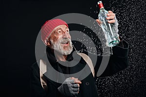 Positive mature homeless man happy to get new bottle of alcohol