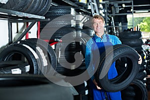 Positive mechanic man standing with car tires