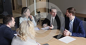 Positive middle aged business man talking to colleagues on meeting