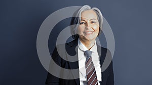 Positive middle-aged businesswoman without mask smiles happily. Optimistic graying woman wearing formalwear posing on