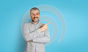 Positive Middle Aged Man Pointing Finger Aside Over Blue Background