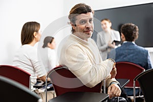 Positive middle-aged man turning around and looking at camera during advanced training course in auditory