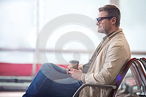 Positive middle-aged traveler is waiting for flight