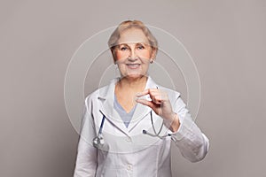 Positive middle-aged woman doctor holding remedy pill