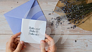 POSITIVE MIND LIFE VIBES text on supportive message paper note reminder from violet envelope. Flat lay composition dry