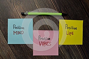 Positive Mind, Positive Vibes, Positive Life write on sticky note isolated on Wooden Table