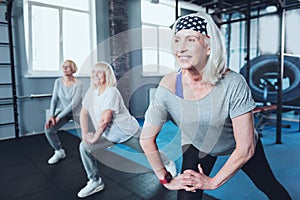 Positive minded elderly ladies doing warmup at fitness club
