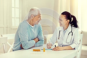 Positive minded elderly man and nurse discussing treatment