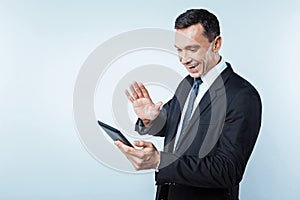 Positive minded gentleman having video call on digital tablet
