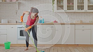 Positive mixed race woman mopping kitchen floor