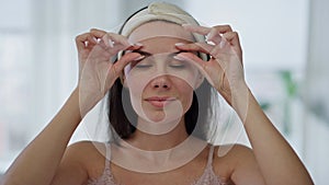 Positive model facial treatment at home mirror pov portrait. Woman face massage