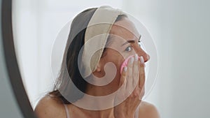 Positive model sponging face looking mirror home closeup. Woman cleaning pores