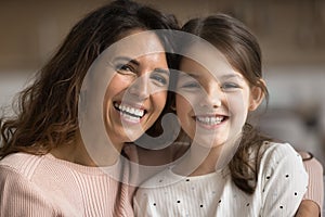 Positive mom and happy tween kid girl looking at camera