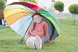 Positive mood in autumn rainy weather. Little girl under colorful umbrella. Rainbow after rain. Multicolored umbrella