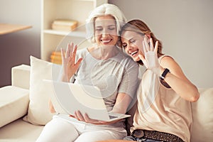 Positive mother and her daughter using laptop