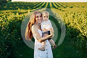 Positive mother with her son spending free time on the field at sunny day time of summer