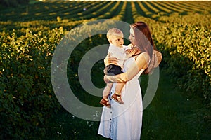 Positive mother with her son spending free time on the field at sunny day time of summer