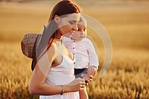 Positive mother with her son spending free time on the field at sunny day time of summer