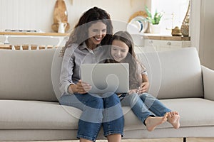 Positive mother and sweet preschool kid girl using computer