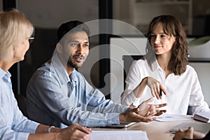 Positive motivated young Indian professional talking to group