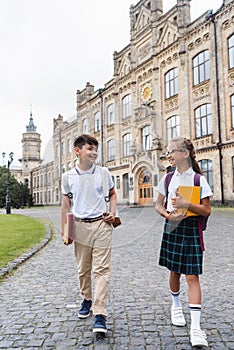 Positive multiethnic schoolkids talking while walking