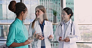 Positive multiethnic team of doctor women talking in clinic office