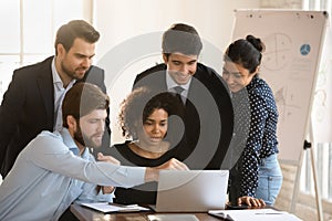 Positive multiethnic team meeting at workplace, looking at computer