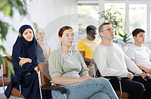 Positive multinational students listening to lecture in classroom