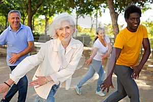 Positive multiracial mature casual pensioners practicing group dancing outdoors in autumn