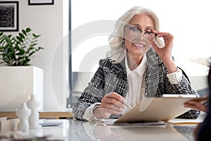 Positive old business woman is signing papers