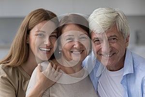 Positive old senior woman hugging mature husband and adult daughter